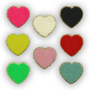 May include: Nine felt heart-shaped patches with gold glitter trim. The hearts are in the colors pink, black, white, yellow, red, light pink, green, and blue.