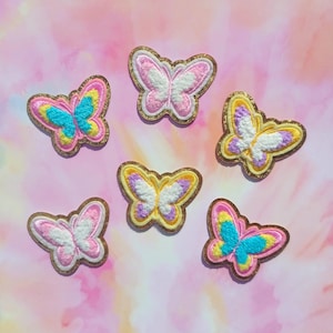 May include: Six colorful embroidered butterfly patches with gold glitter accents. The butterflies are pink, yellow, blue, and white.