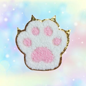 May include: A white and pink fuzzy cat paw print with a gold glitter outline.