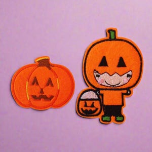 May include: Two embroidered iron-on patches featuring a pumpkin design. One patch is a simple pumpkin with a carved face, while the other is a cartoon pumpkin character holding a trick-or-treat bag.