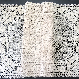 May include: An off-white, intricately designed lace doily. The lace features floral and geometric patterns, with a scalloped edge. The doily is folded, revealing the detailed texture and craftsmanship. This delicate piece is suitable for home decor.