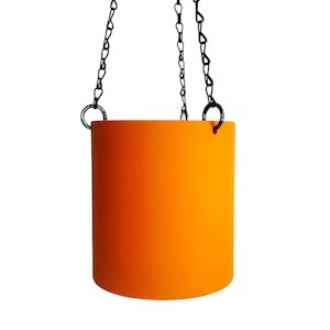 Könnte beinhalten: Orangener Hängepflanztopf mit einer schwarzen Kette.