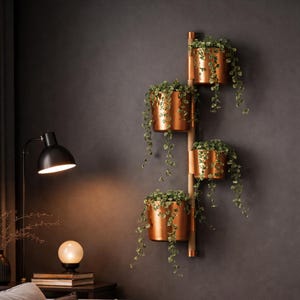 Può includere: Un portapiante da parete con quattro vasi color rame, ciascuno pieno di piante verdi pendenti. Il supporto è realizzato in legno e rame, creando un design moderno e minimalista. I vasi sono cilindrici e appesi verticalmente.