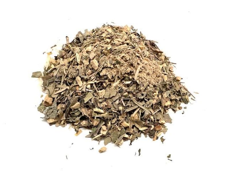 May include: A pile of dried herbs and spices, featuring a mix of green, brown, and tan colors. The blend appears to be a mix of leaves, stems, and ground spices, with a variety of textures. The background is plain white.