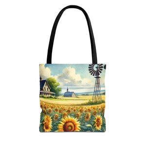 Könnte beinhalten: Tragetasche mit einem Aquarellgemälde einer ländlichen Landschaft. Das Design zeigt ein Bauernhaus, eine Windmühle und ein Feld mit Sonnenblumen unter blauem Himmel mit Wolken. Die Tasche hat einen schwarzen Griff.