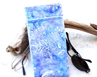 May include: A blue and white floral patterned glasses case. The case is rectangular and has a soft, fabric appearance. A pair of eyeglasses and sunglasses are next to the case.