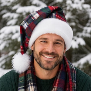 May include: A holiday hat featuring a red, green, and blue plaid pattern with a thick white faux fur brim and a white pom-pom at the tip. The hat is constructed from fabric and includes a soft, plush white band that encircles the base of the head.