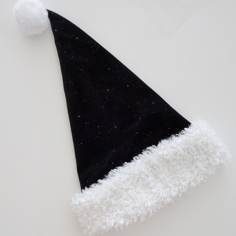 May include: A black Santa hat with a white fluffy trim and a white pom-pom at the tip. The hat is covered in tiny, colorful glitter, giving it a festive, sparkling appearance. This holiday accessory is perfect for Christmas celebrations.