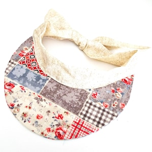 Cappello da sole con visiera in tessuto patchwork floreale e lacci regolabili.