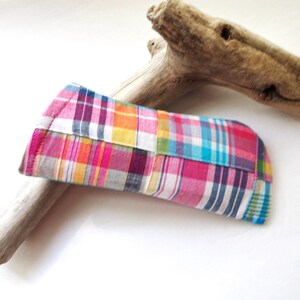 K&ouml;nnte beinhalten: Ein bunt kariertes Brillenetui in Rosa, Blau, Gelb und Wei&szlig;. Das Etui ist rechteckig mit gew&ouml;lbter Oberseite und besteht aus Patchwork-Stoff. Ein St&uuml;ck Treibholz liegt im Hintergrund.