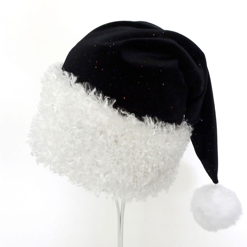 May include: A black Santa hat with a white, fluffy trim and a white pom-pom. The hat is made of a soft, velvety material and has small, colorful glitter accents. The hat is a festive accessory for the holiday season.