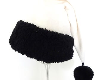 May include: A white Santa hat with a black fuzzy trim and a black pom-pom at the end. The hat is made of soft material and is designed to be worn during the Christmas holiday season.