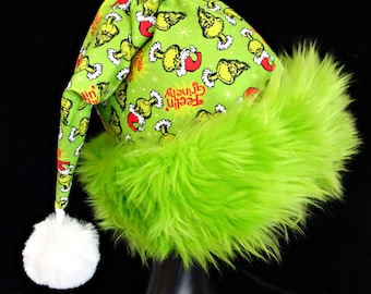 May include: Green Grinch Christmas hat with a white pom pom and a green fur trim. The hat is decorated with a repeating pattern of the Grinch's face and the words "Feeling Grinch-y".