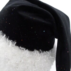 May include: A black Santa hat with a white, fluffy trim. The hat is sprinkled with colorful glitter. The hat is made of a soft fabric and has a long, pointed shape.