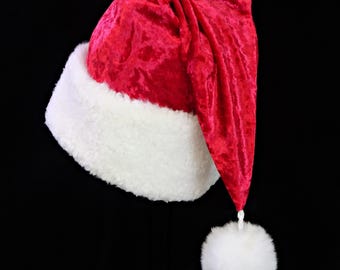 May include: A red Santa hat with a white fluffy trim and a matching pom-pom. The hat is made of a soft, velvety material and is designed to be worn during the Christmas holiday season.