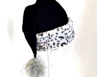 May include: A black fabric hat with a long, drooping top section and a white faux fur brim featuring a black leopard print pattern. A large, fluffy, light gray pom-pom is attached to the tip of the hat, which hangs down from the main body.