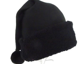 May include: A black Santa hat with a soft, fuzzy brim and a matching pom-pom. The hat is made of a smooth, dark fabric and has a long, pointed tip. The brim is a contrasting texture, adding visual interest to the festive headwear.