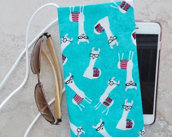 May include: A turquoise phone pouch with a white drawstring closure. The pouch features a repeating pattern of llamas wearing glasses. The pouch is lying on a white surface next to a pair of sunglasses.