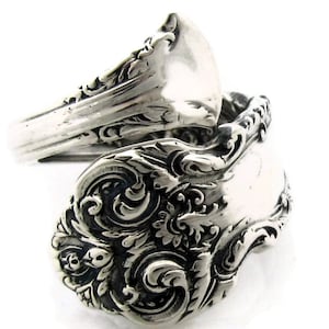 Peut inclure: Une bague en argent fabriquée à partir d'une cuillère vintage avec un motif orné. La cuillère est pliée en forme de bague et le bol de la cuillère forme le visage de la bague.