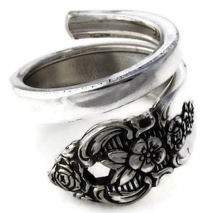 May include: A silver ring made from a twisted silverware spoon with a floral design.