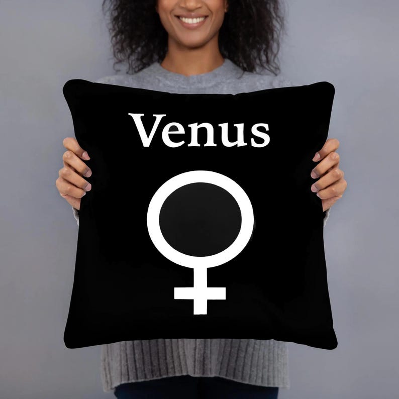 May include: A square black throw pillow featuring the white text Venus centered at the top, positioned above a large white Venus symbol. The design is printed on the front of the pillow, which has a solid black background and clean edges.