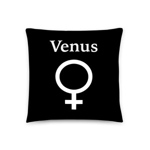 May include: A square black throw pillow featuring the white text Venus centered above a large white female gender symbol. The design is printed on the front of the pillow, creating a high-contrast graphic appearance against the solid black background.