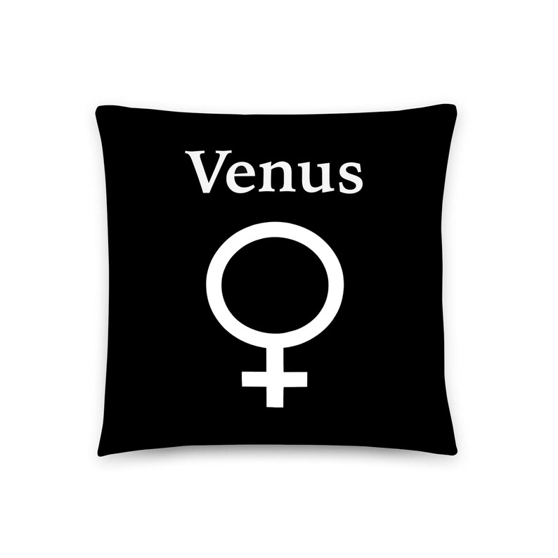 May include: A square black throw pillow featuring the white text Venus centered above a large white female gender symbol. The design is printed on the front of the pillow, creating a high-contrast graphic appearance against the solid black background.