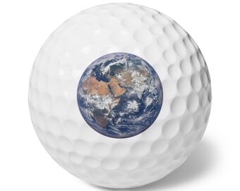 May include: A white golf ball with a dimpled surface featuring a circular, detailed photographic print of the Earth centered on its side, showing the continents of Africa and Europe with blue oceans and white cloud formations.