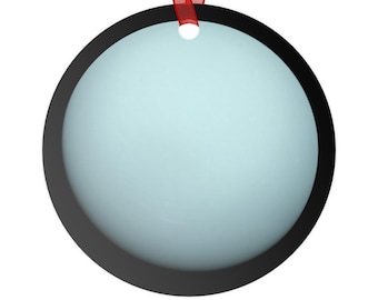 May include: A circular ornament featuring a solid light blue center surrounded by a thick black border. The ornament has a small hole at the top, through which a thin red ribbon is threaded for hanging purposes.