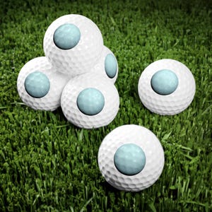 May include: A collection of five white golf balls, each featuring a smooth, light blue circular inlay on its surface. The golf balls have a dimpled texture and are arranged in a cluster, with four balls stacked together and one positioned separately.