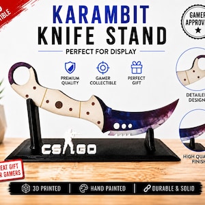 Può includere: Una replica di coltello Karambit su un supporto nero. L'impugnatura è di colore chiaro con fori circolari e la lama curva presenta una sfumatura viola e blu. La base include la scritta CS:GO e una piccola sagoma di un soldato.