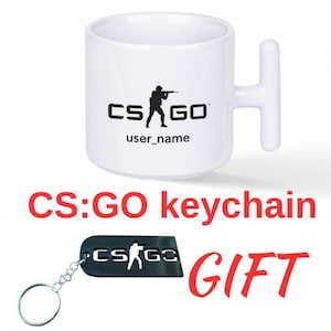 Puede incluir: Taza de cerámica blanca con un asa única, con el logotipo "CS:GO" y una silueta de un soldado apuntando con un rifle. Debajo de la taza hay un llavero negro con el mismo logotipo. El texto "user_name" está debajo del logotipo en la taza.