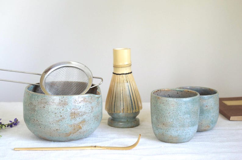 Handmade ceramic matcha set featuring a deep teal blue bowl with pouring spout and whisk holder. With a 19oz capacity, it’s ideal for slow tea rituals and matcha lovers who enjoy generous servings in a calm, rustic setting with artisan details.