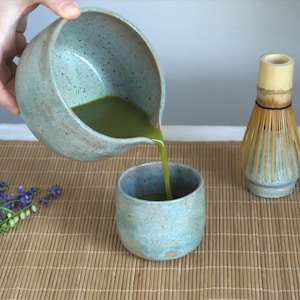 Large capacity matcha bowl with spout in matte teal glaze, styled with bamboo whisk and spoon. This 550 ml chawan is perfect for daily wellness routines and those who appreciate handmade ceramics and intentional tea moments.