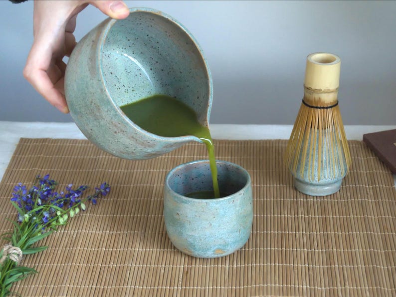 Large capacity matcha bowl with spout in matte teal glaze, styled with bamboo whisk and spoon. This 550 ml chawan is perfect for daily wellness routines and those who appreciate handmade ceramics and intentional tea moments.