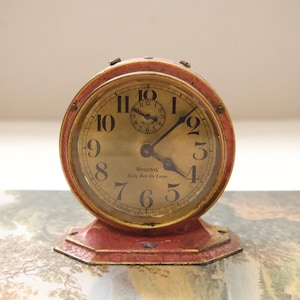 May include: A set of three ceramic mugs with a speckled, cream-colored glaze. Each mug features a different hand-painted design: a blue and green leaf, a yellow flower, and a red berry. The mugs have a simple, rounded shape.