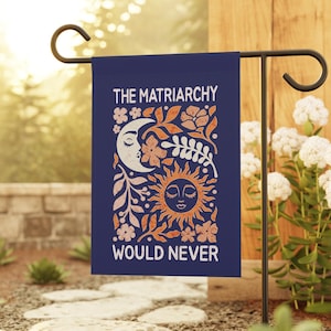 May include: A rectangular dark blue garden flag featuring the white text THE MATRIARCHY WOULD NEVER. The design includes a stylized orange and white crescent moon with a face, a sun with a face, and various floral and leaf illustrations.