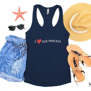 May include: Navy blue racerback tank top with the text "I ❤️ DUE PROCESS" in white and red. The image also includes denim shorts, sunglasses, a straw hat, sandals, and a starfish.