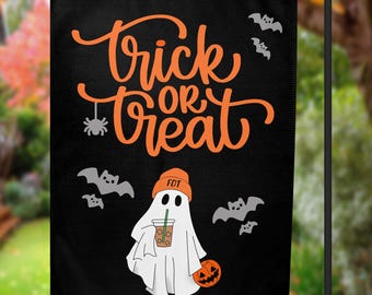 May include: A black rectangular garden flag featuring the orange text Trick or Treat in a cursive font. Below the text is a white ghost wearing an orange beanie with FDT printed on it, holding an iced coffee and a small orange jack-o'-lantern.