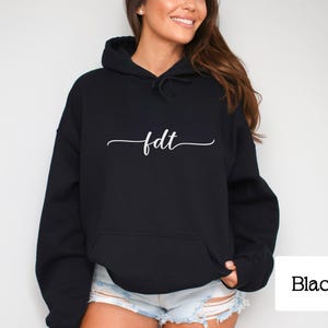 May include: Black hooded sweatshirt with the word "fdt" written in white cursive script.