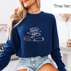 May include: A navy blue long-sleeved shirt with a white outline of a lotus flower on the front. The shirt has a crew neck and is made of a soft, comfortable material.
