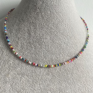 Può includere: Una collana di perline colorate con una varietà di colori, tra cui rosso, arancione, giallo, verde, blu, viola e bianco.