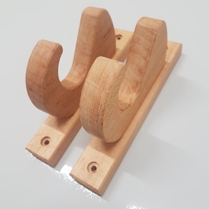 Peut inclure: Deux crochets muraux en bois avec un design incurvé. Les crochets sont montés sur une base en bois et ont une finition en bois naturel.