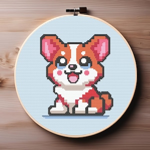 Puede incluir: Un aro de bordado de punto de cruz con una imagen pixelada de un perro corgi marrón y blanco con orejas rosas y una expresión feliz.