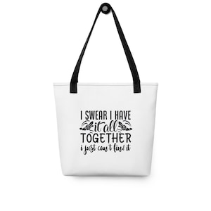 Puede incluir: Bolsa de tela blanca con asas negras y el texto "I swear I have it all together I just can't find it" con un diseño floral.