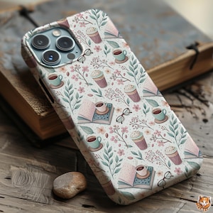 May include: A phone case with a repeating pattern of coffee cups, books, eyeglasses, and floral elements in shades of pink, green, and brown. The case is on a wooden surface with a book.