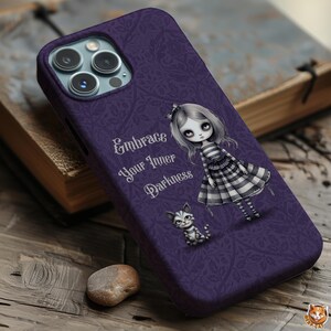 May include: Purple phone case with a floral pattern, featuring a gothic doll and a kitten illustration. The text "Embrace Your Inner Darkness" is displayed in white script. The case is designed for a smartphone.