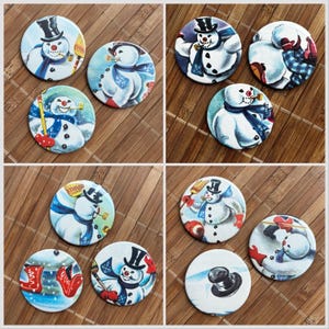 Puede incluir: Una colección de chapas circulares con diversas ilustraciones de muñecos de nieve. Cada chapa muestra un muñeco de nieve con sombrero de copa negro y bufanda azul, a menudo sosteniendo una escoba o pipa, sobre fondos nevados con detalles rojos.
