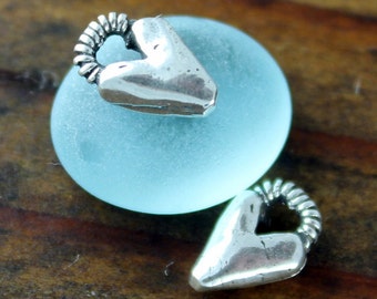 May include: Two silver heart-shaped charms with a twisted wire detail. The charms are on a light blue background.