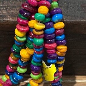 May include: Close-up of colorful beaded necklaces. The beads are in various colors, including yellow, green, blue, purple, and pink. The beads are strung together, creating a vibrant and eye-catching accessory.